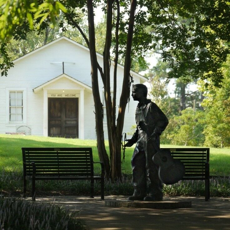 Statue of young Elvis with a guitar in front of family chapel. 