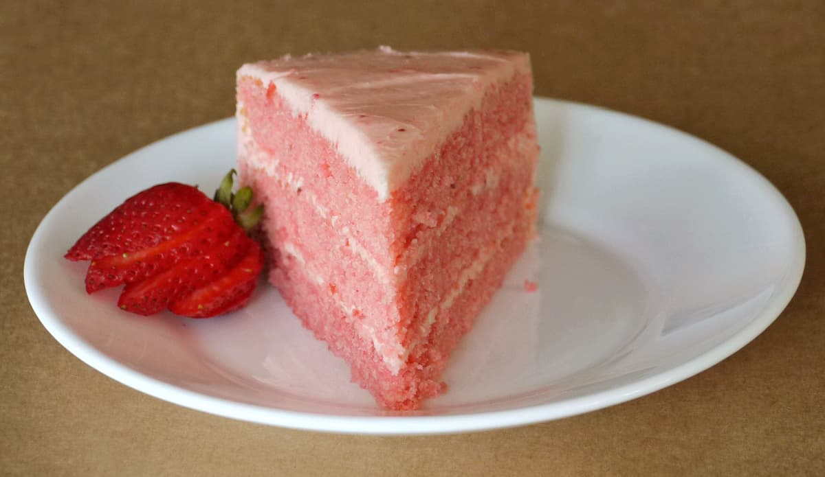 Close-up of a slice of 3-layer strawberry cake on plate.