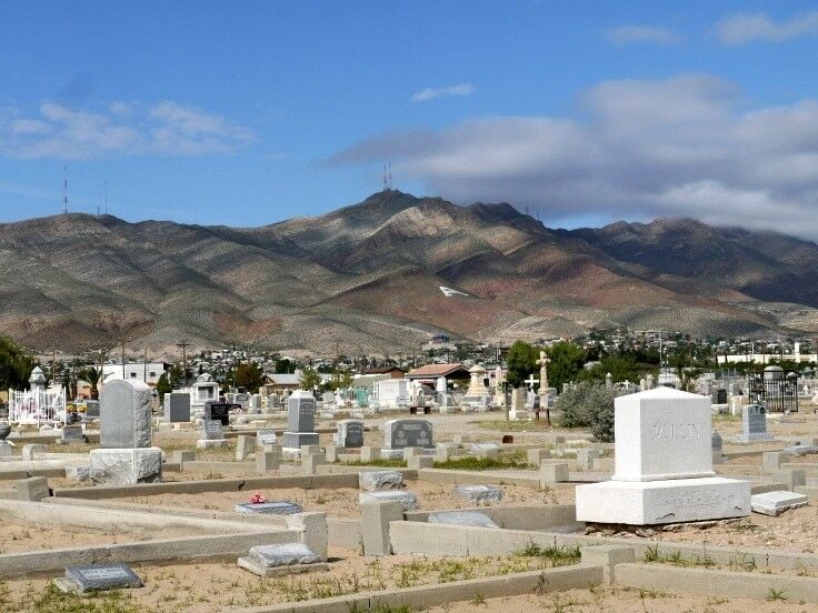 Landscape shot of cemetery, look up toward the hills. Cloud shadows falling on hills. 