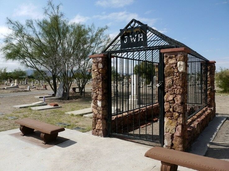 Enclosure the size of a one car garage made of red rocks and iron bars. Sign above the entrance: JWH. 