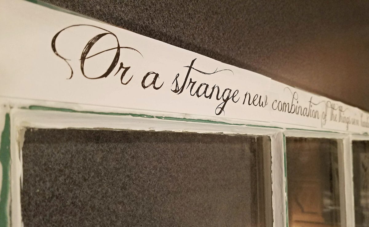 Quote painted across the top of an old window frame.