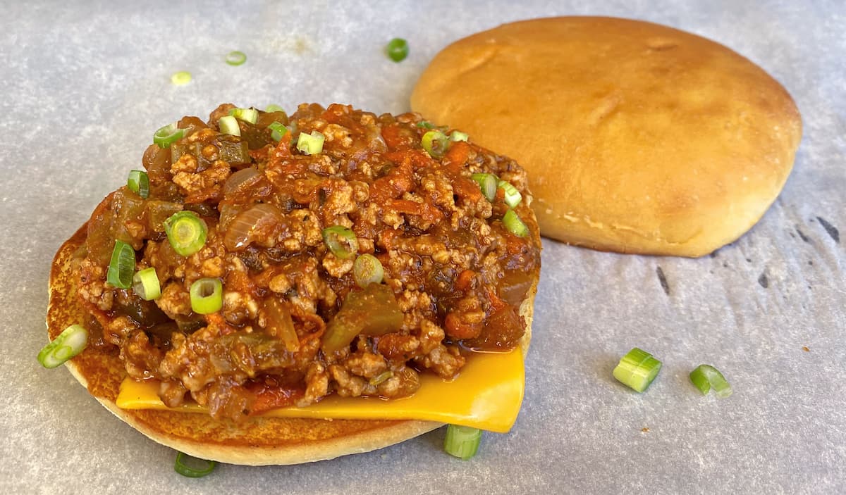 Sloppy joes assembled on a piece of parchment. Top bun to the side.