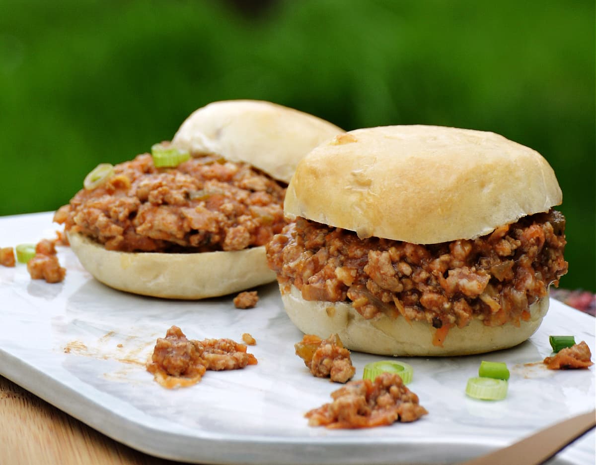 Two prepared sloppy joes on a small cutting board.