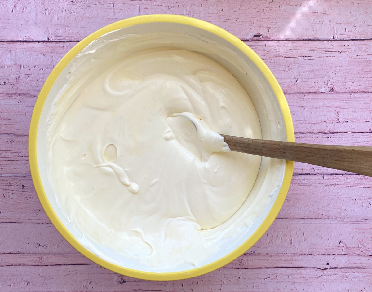 Large mixing bowl with vanilla pudding and Cool Whip fully combined into a smooth, creamy mixture.