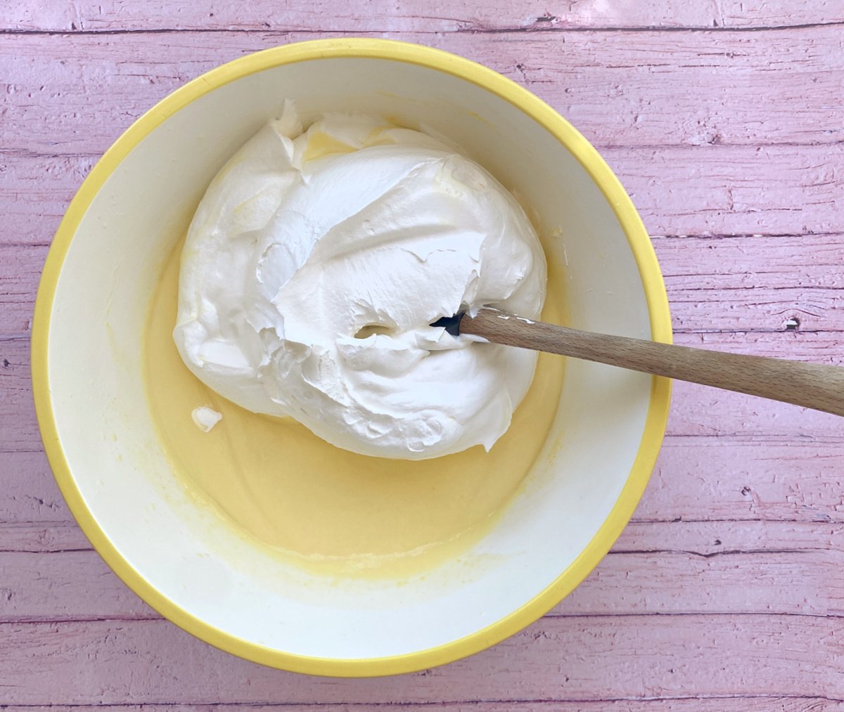 Large glass bowl filled with vanilla pudding and a scoop of Cool Whip on top, not yet mixed together.