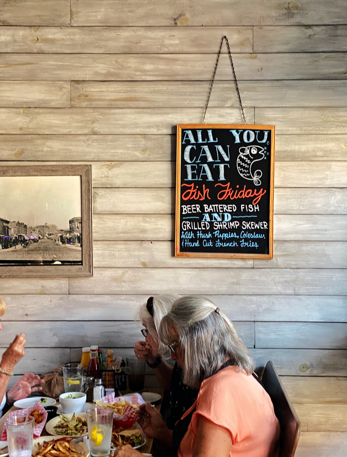 Interior of Southside Grill, showing a table of older women eating lunch, with a sign hanging above them. 