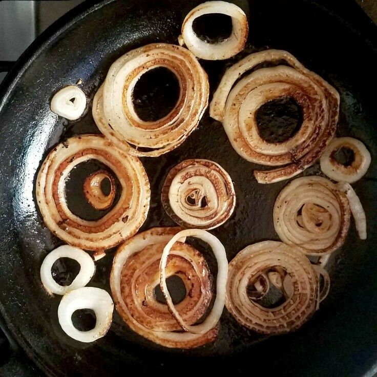 Onion slices frying in a cast iron skillet.