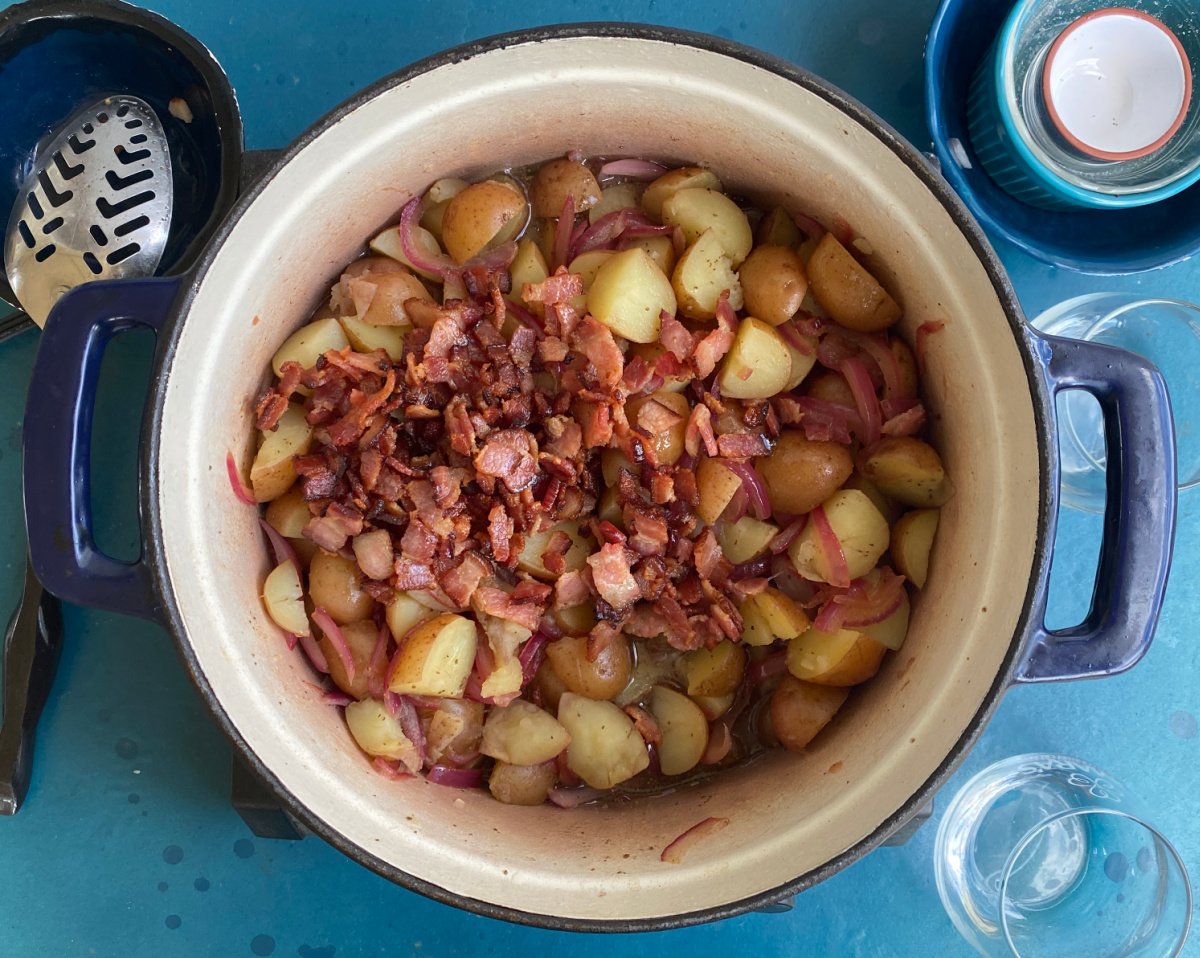 Added cooked bacon pieces to potatoes in Dutch oven.