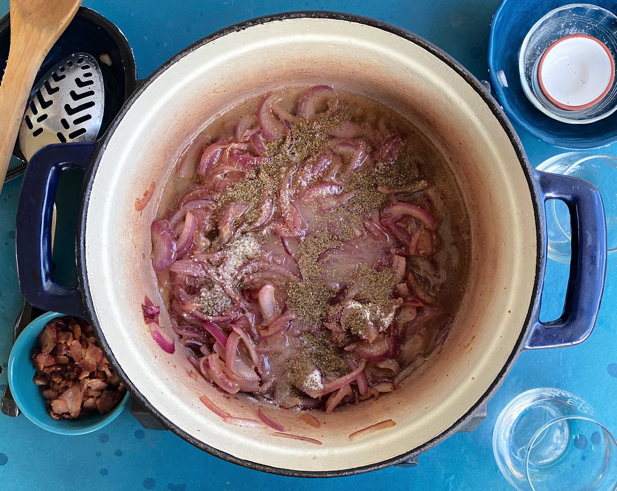Overhead shot of sauteed red onions with. vinegar, sugar, water and celery seed in Dutch oven.
