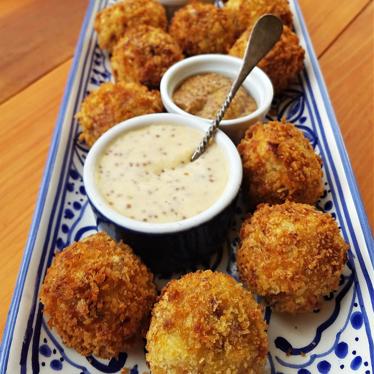 Sauerkraut fritters on a blue and white tray, served with dipping sauces.