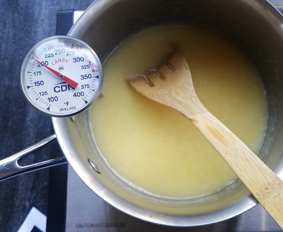Caramel in stockpot, with candy thermometer clipped on. Thermometer reads 200°F.