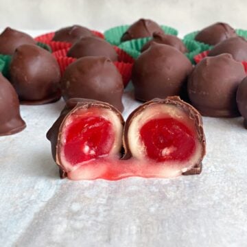 Chocolate covered cherry cut in half and opened on parchment.