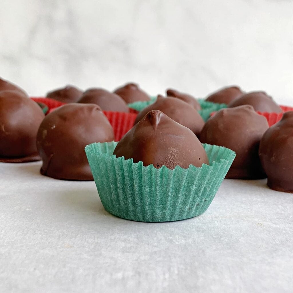 Close-up of a dipped chocolate in green fluted candy cup.
