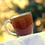 Russian tea in a glass mug, with sunlight mottled in the background.