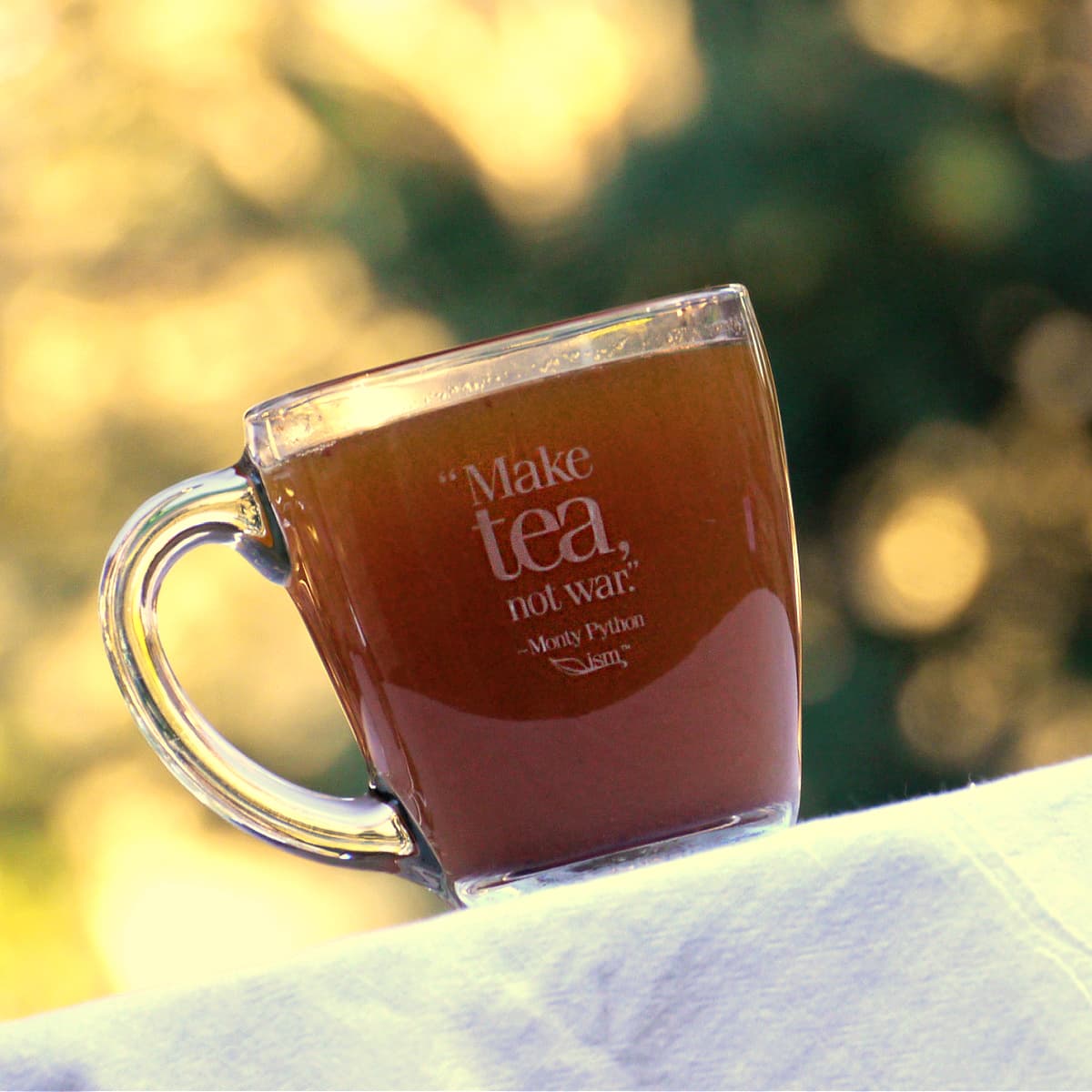 Tea in a glass mug on which is etched: "Make tea, not war." ~ Monty Python 