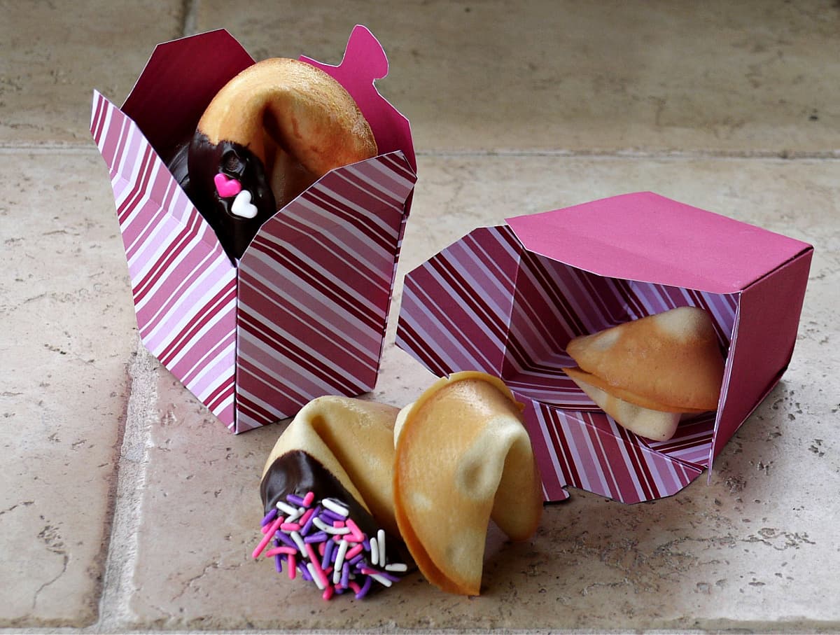 Fortune cookies and takeout boxes with pink, white, and purple sprinkles.