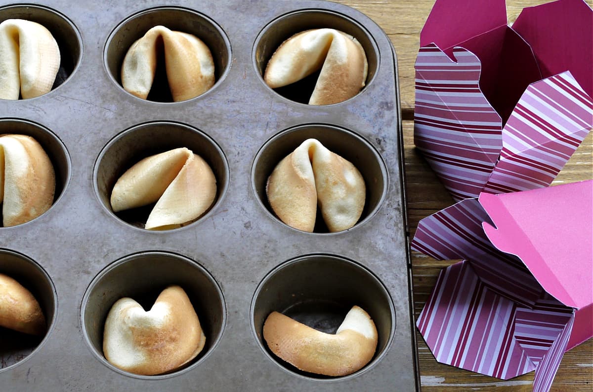 Fortune cookies cooling to shape in muffin tin.