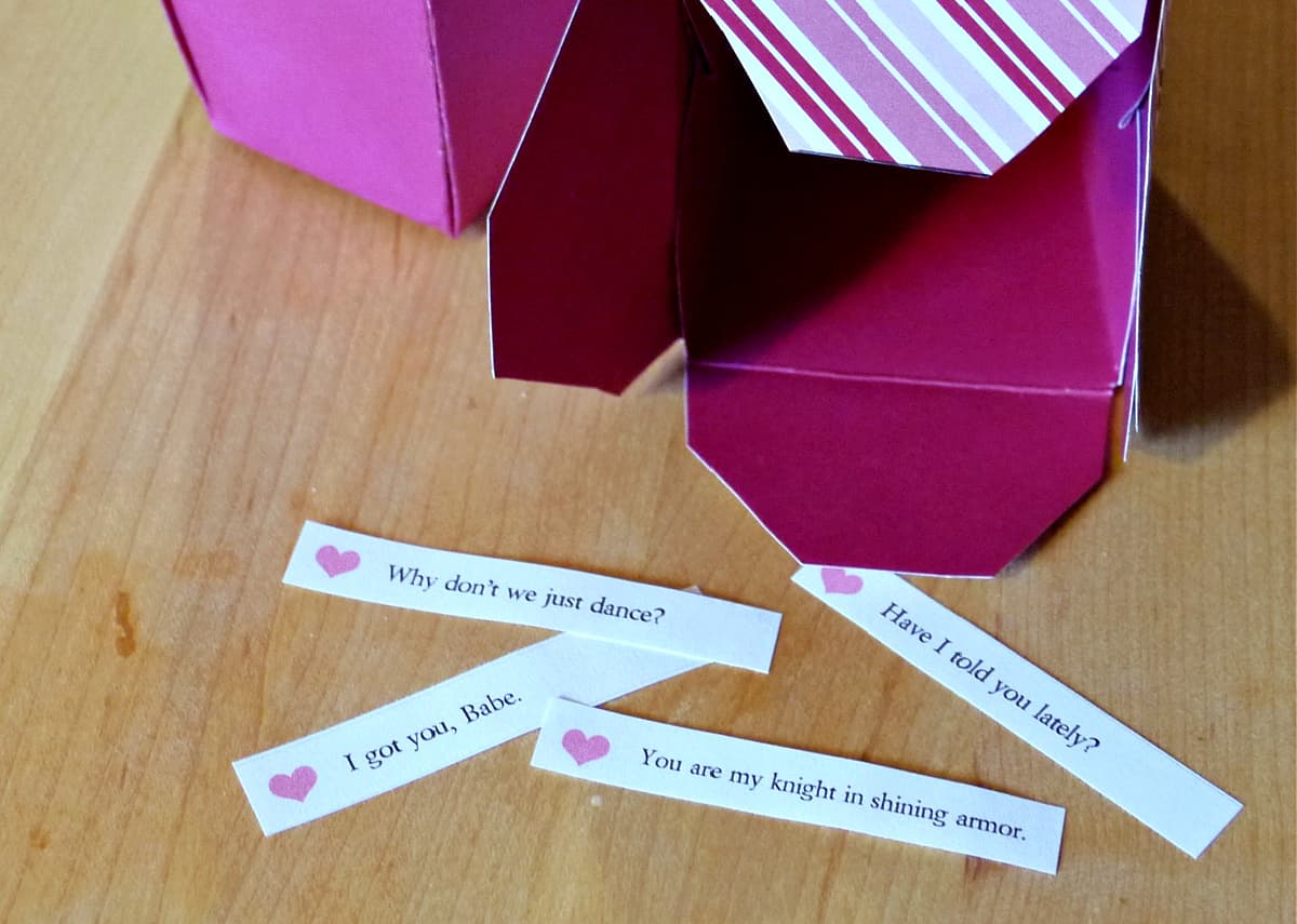 Four cut out fortunes for fortune cookies laying on a wooden table.  