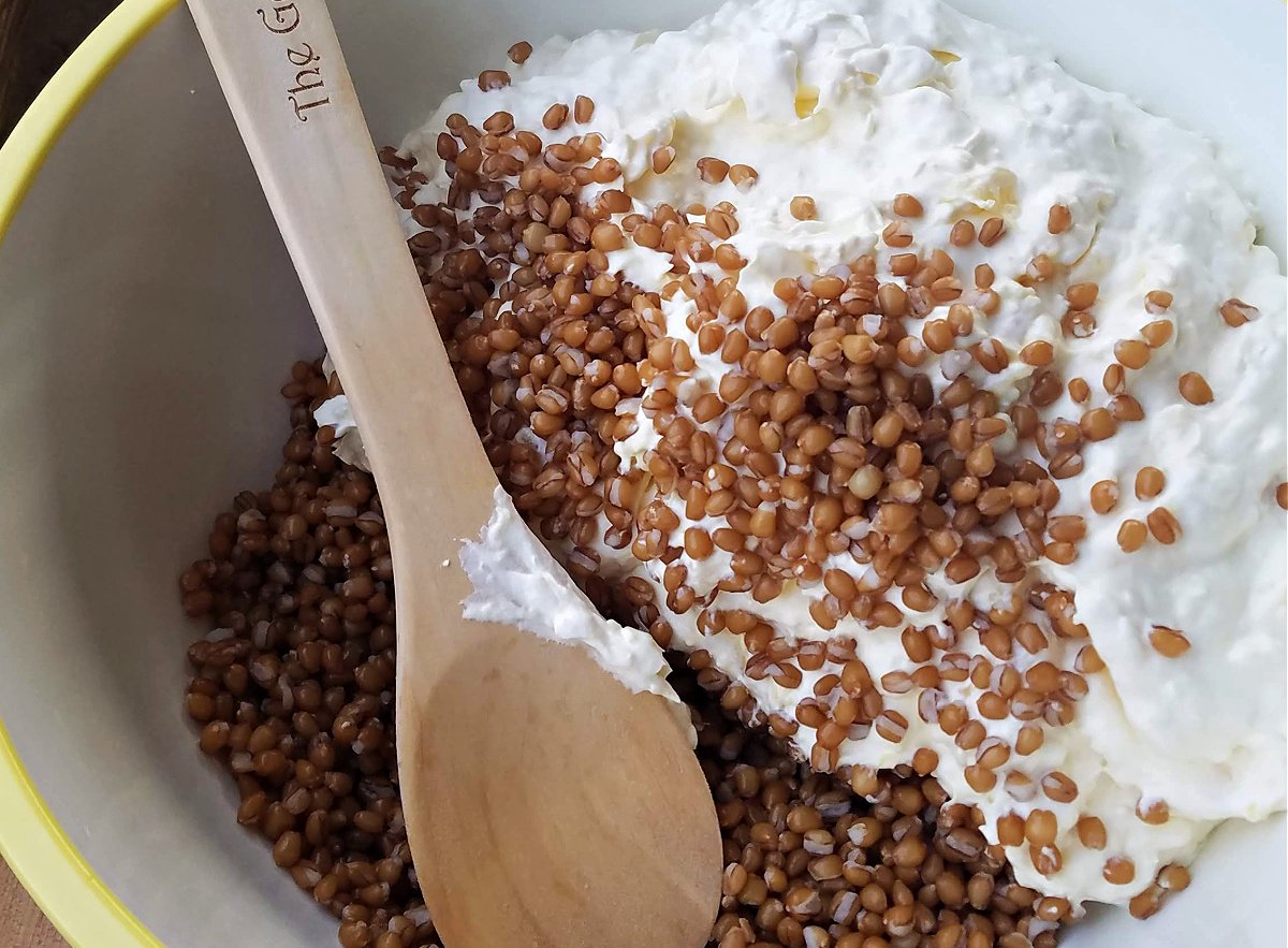 wheat berries and white fluffy salad in a large yellow mixing bowl.