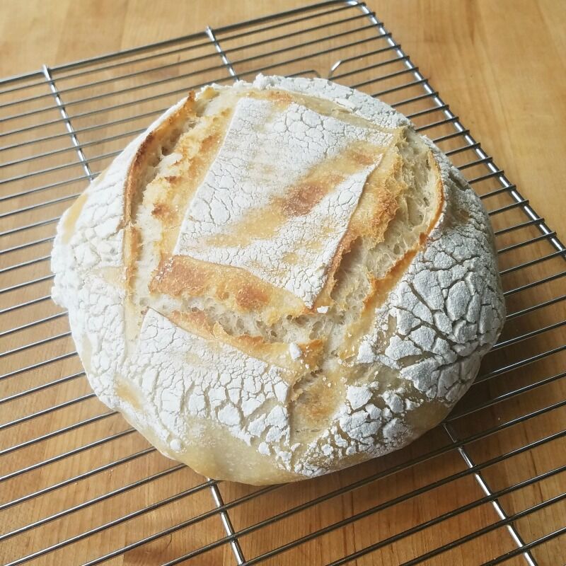 Loaf of easy sourdough bread baked and cooling on a wire rack.