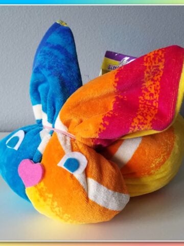 Brightly colored towel formed into a bunny shape, with felt eyes and nose.