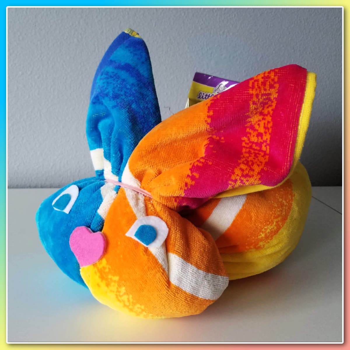 Brightly colored towel formed into a bunny shape, with felt eyes and nose. 