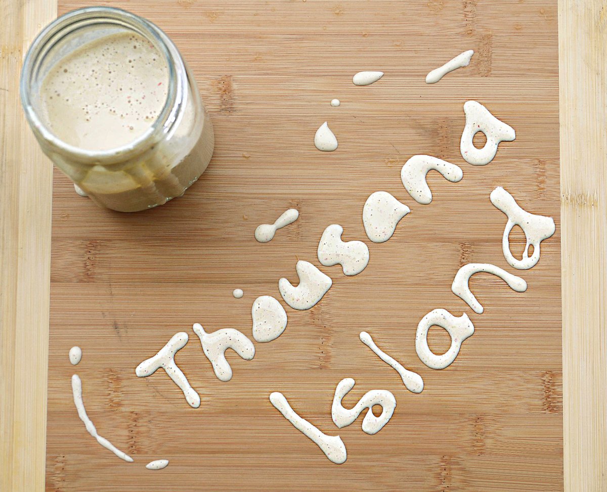 Cutting board with the words "Thousand Island" spelled out in dressing.