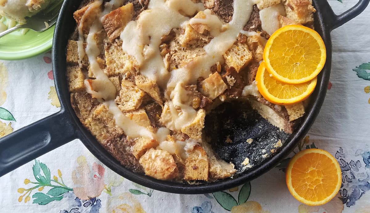 Bread pudding in a cast iron skillet, garnished with orange slices.