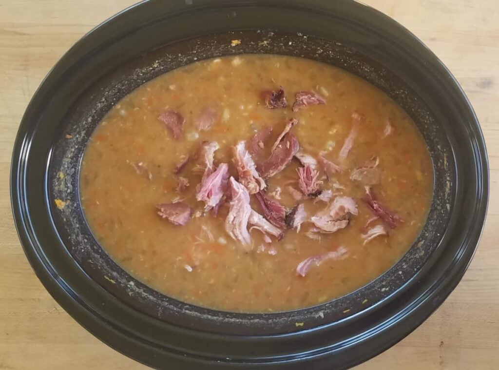 Ham floating on top of pureed bean soup mixture, in slow cooker. 