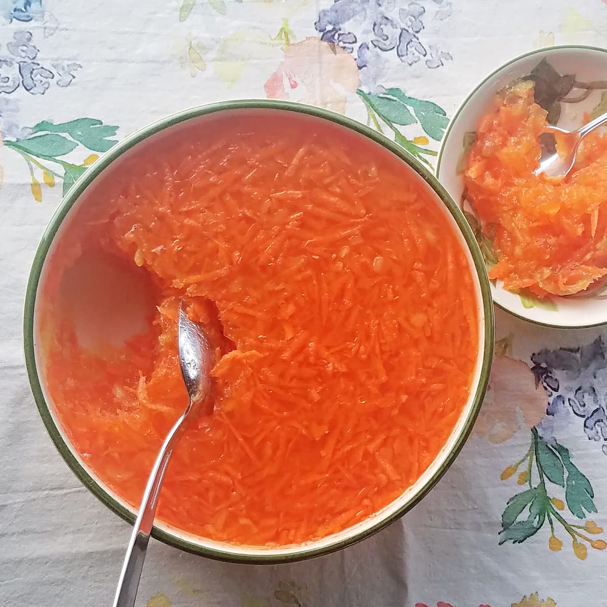 Orange jello salad in green-rimmed serve bowl with serving spoon. 