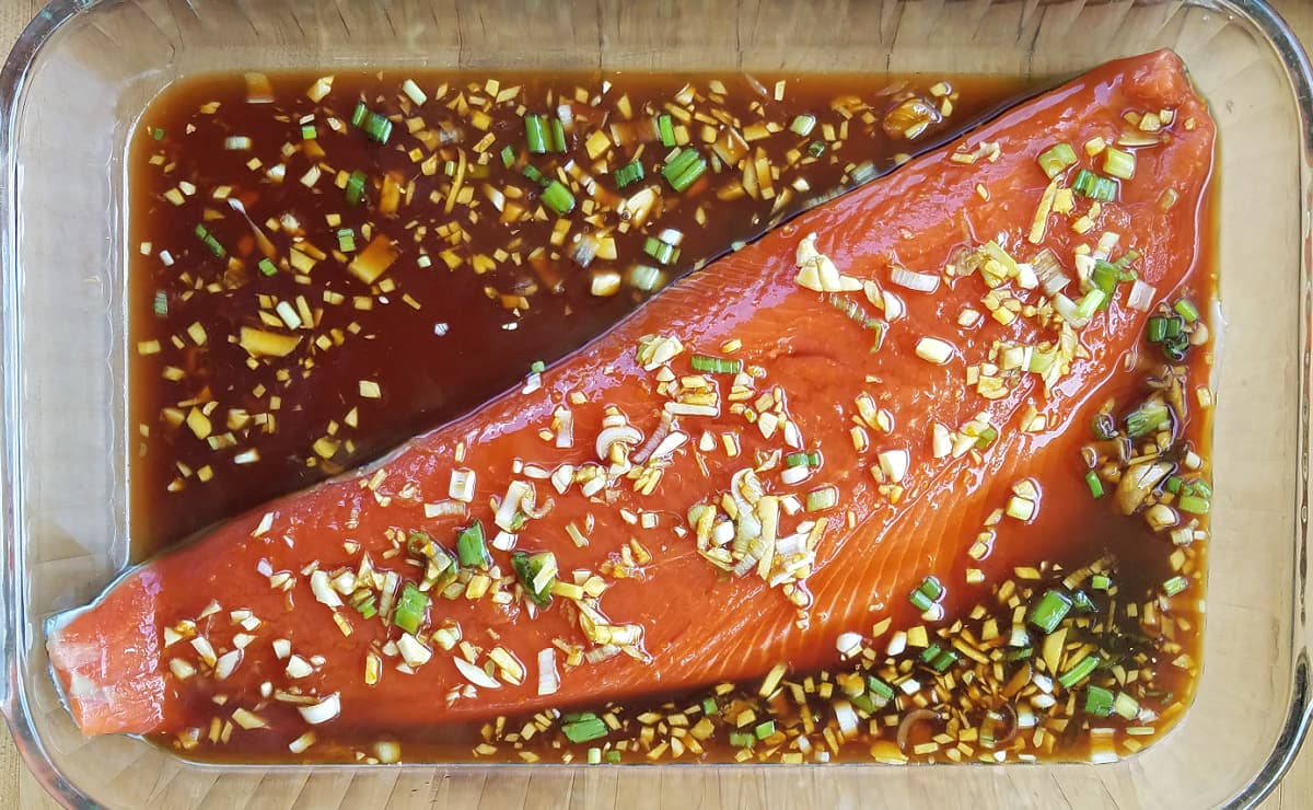 Large salmon fillet in 13x9 glass casserole dish, laying flesh-side-up in marinade. 