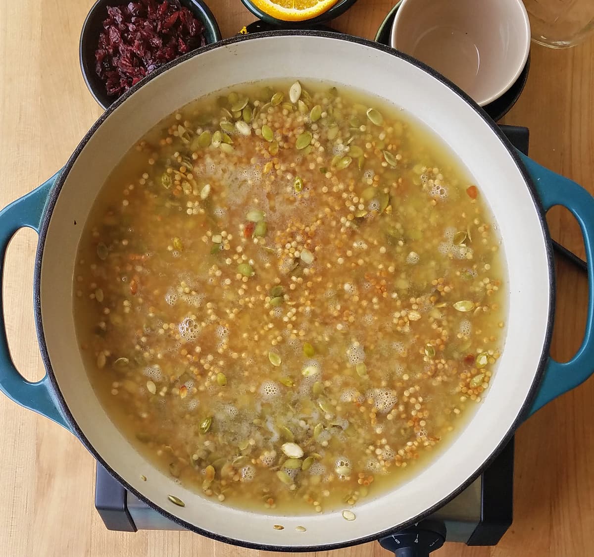 Broth added to skillet, with couscous and other ingredients submerged in broth.