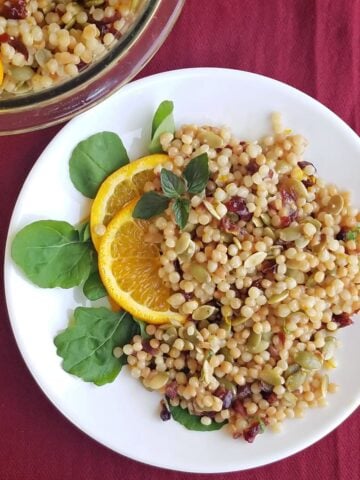 Plate of couscous garnished with orange slices and fresh mint.