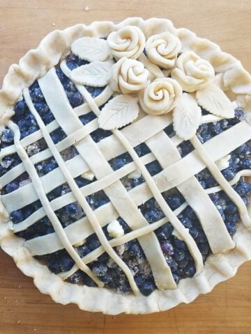 Unbaked, latticed topped blueberry pie, decorated with pie dough roses.