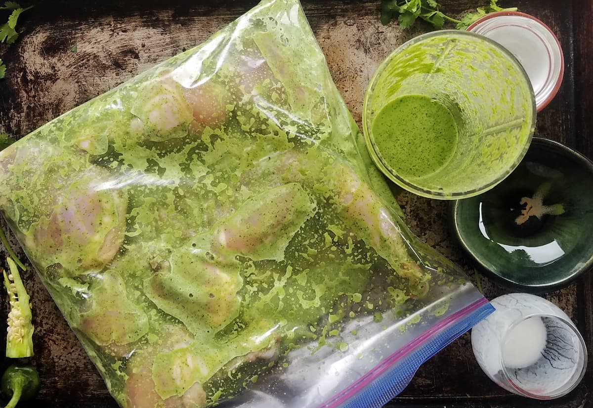 Chicken with green marinade sealed in a large ziploc bag. 