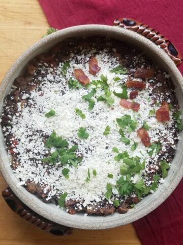 Round crockery casserole dish filled with cotija covered black beans