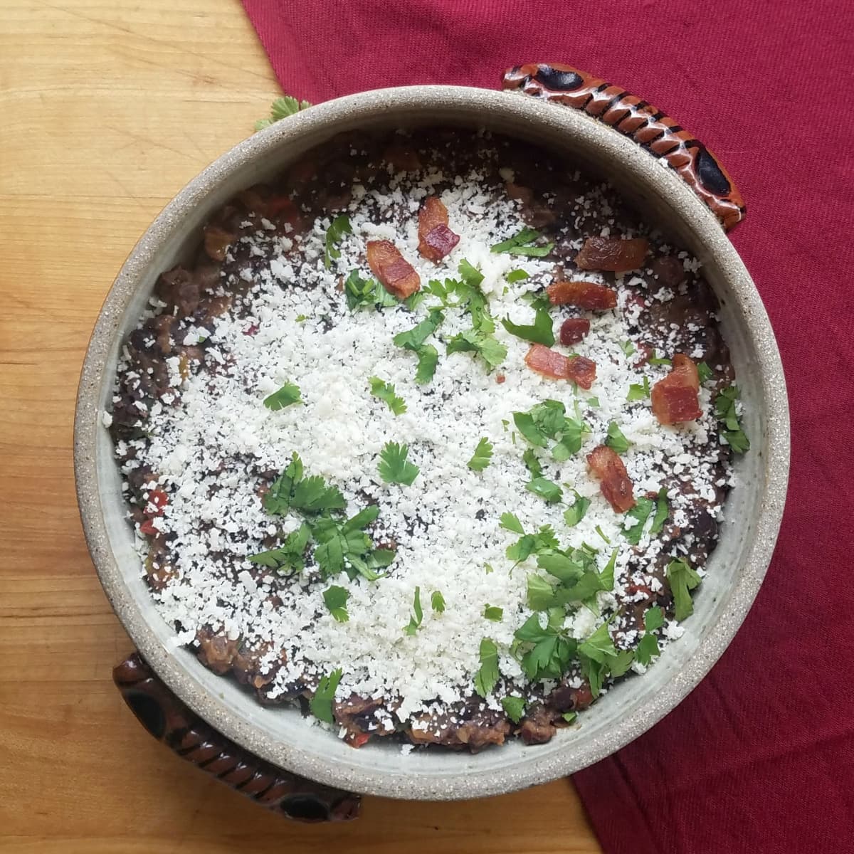 Round crockery casserole dish filled with cotija covered black beans