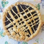 Freshly baked blueberry pie with lattice top adorned with pastry flowers.