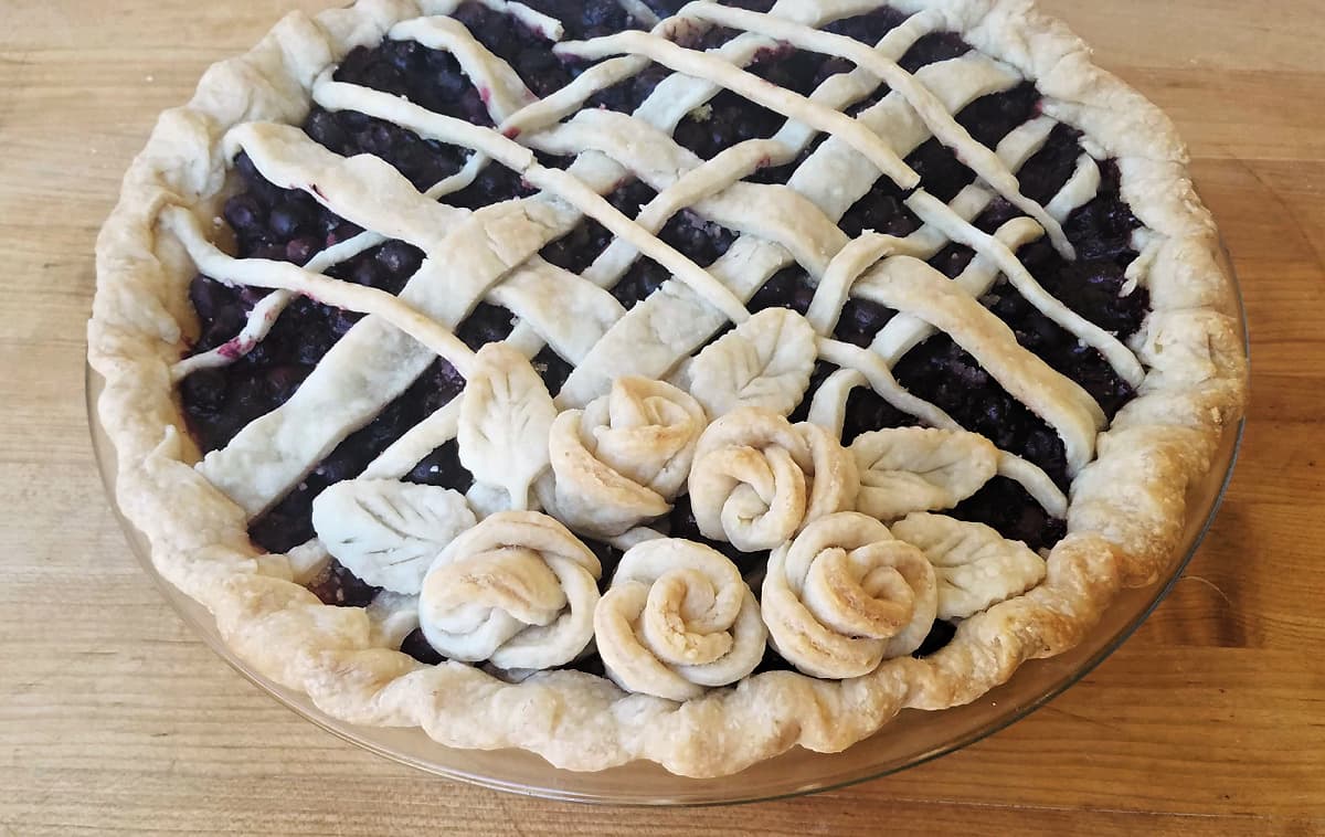 45-degree shot of baked blueberry pie, decorated with pastry roses.