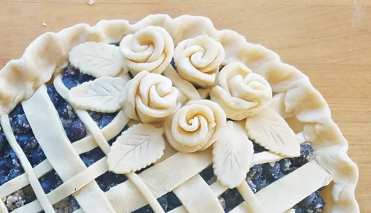Unbaked blueberry pie decorated with lattice top and pie dough roses.