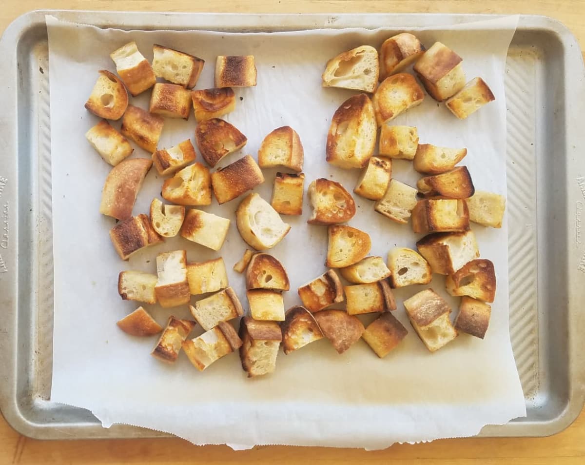Bread cubes on baking tray lined with parchement, toasted.