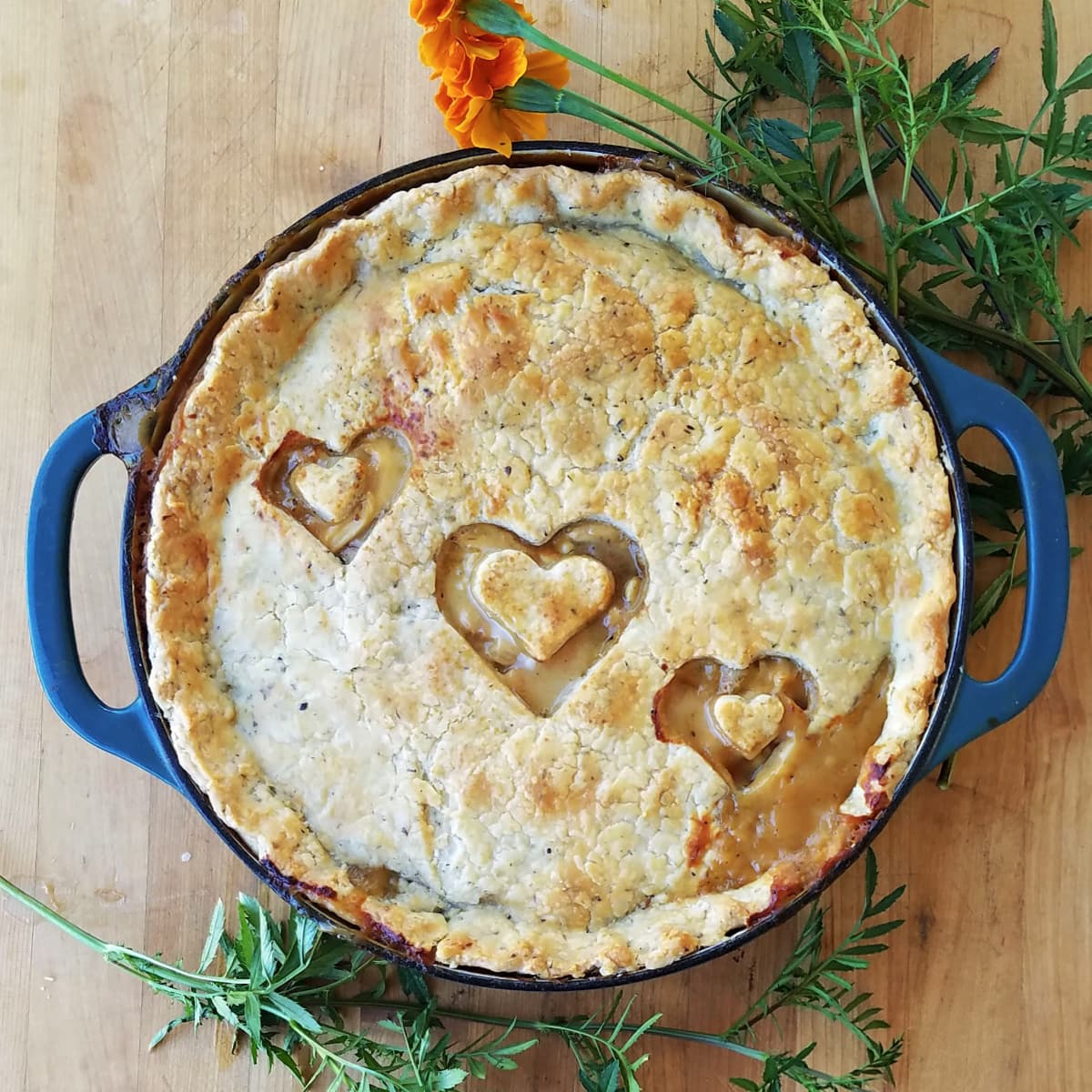 Large enamel cast iron skillet with baked chicken pie, the crust vented with three hearts. 