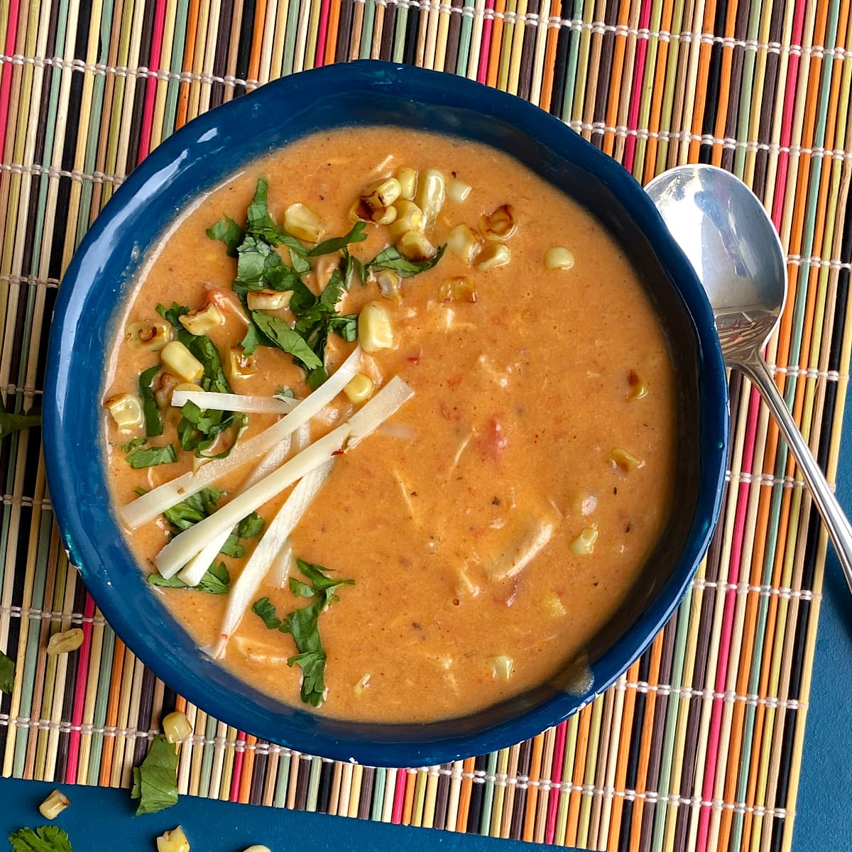 Enchilada soup in hand-built clay bowl, garnished with corn, tortilla strips, and cilantro.