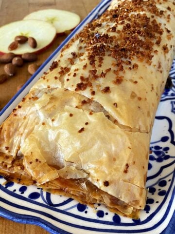 Close-up of a whole apple strudel on a long serving plate.