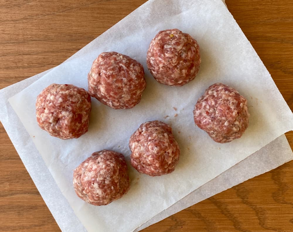 Six sausage balls on parchment. 