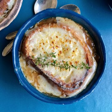 French onion soup, topped with cheese and garnished with fresh thyme.