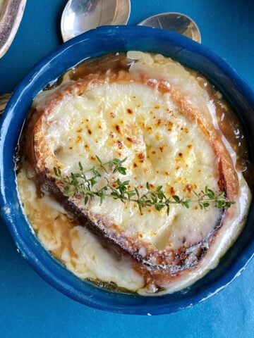 French onion soup, topped with cheese and garnished with fresh thyme.