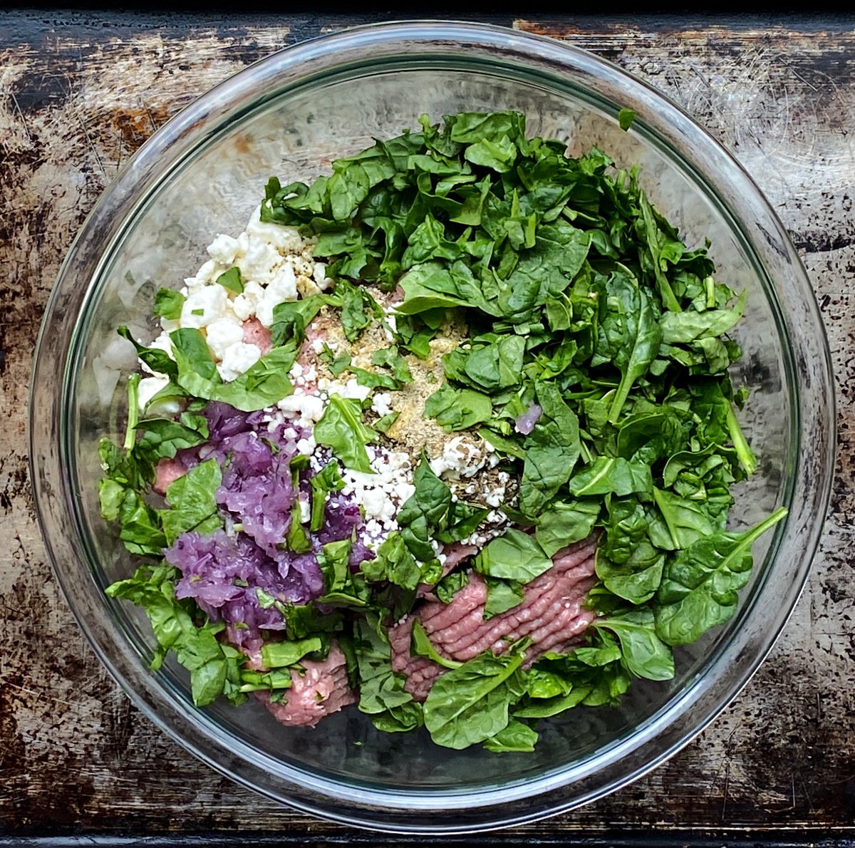 Burger ingredients unmixed, in glass bowl.