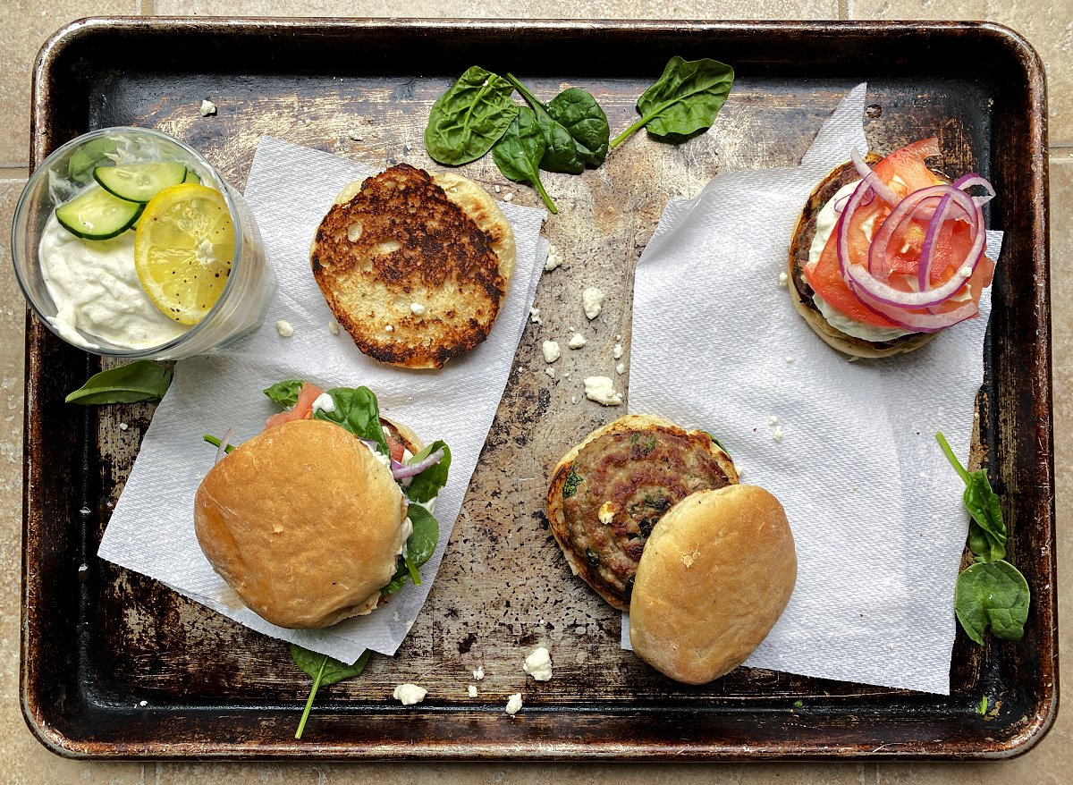 Prepping cooked burgers on old baking tray. 