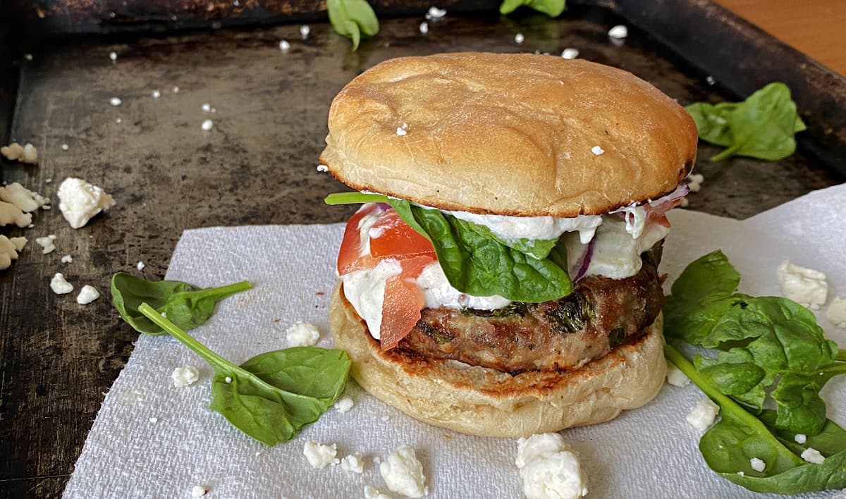 Close-up of Greek Turkey Burger with spinach and feta around it. 